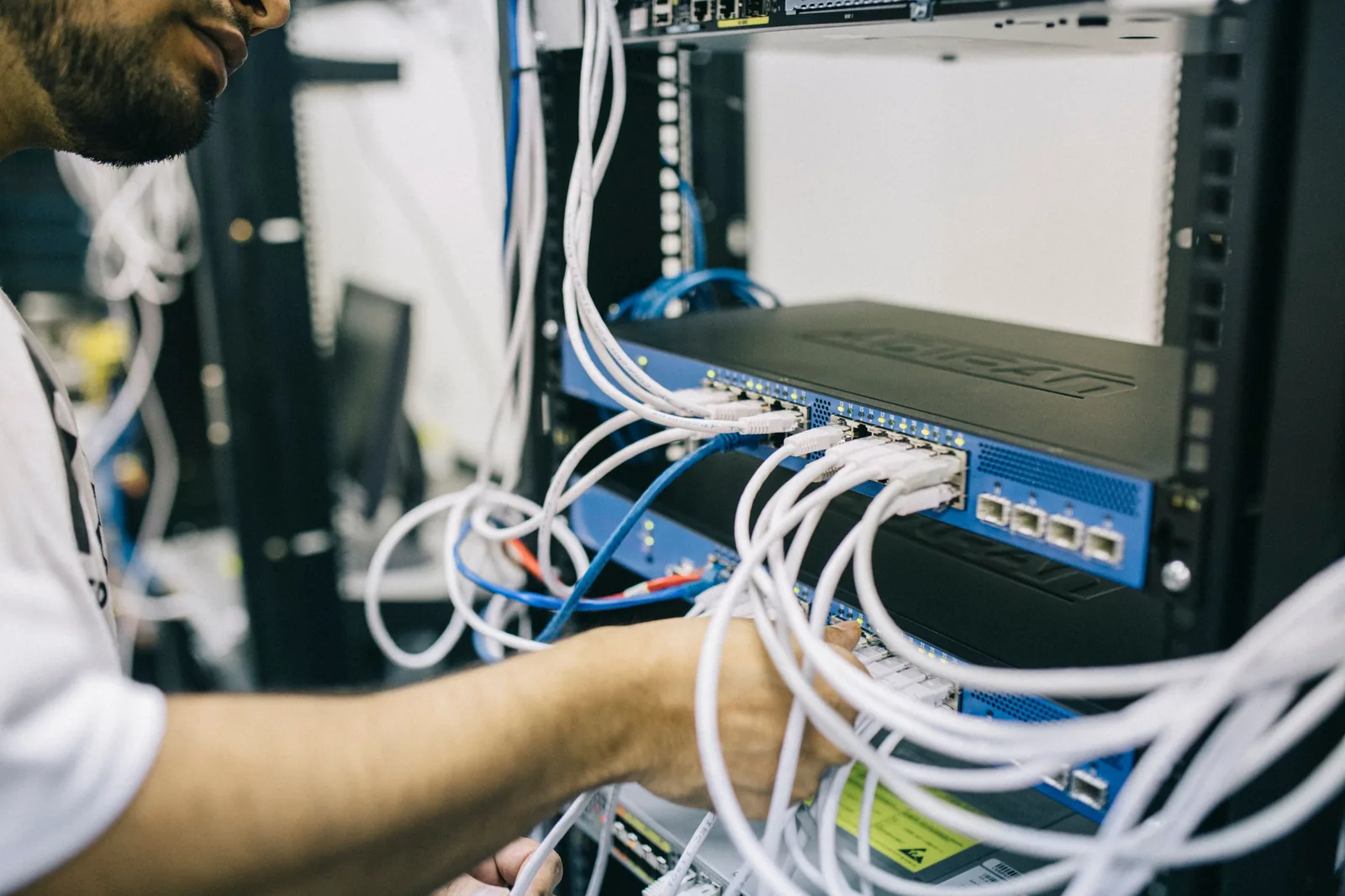 Técnico trabajando en cableado y equipo de red instalado en rack